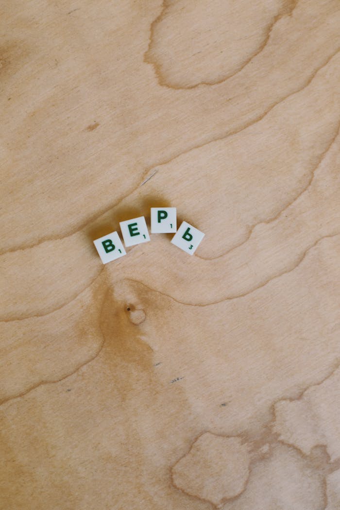 Cyrillic letter tiles on a wooden surface representing a word in Russian language.